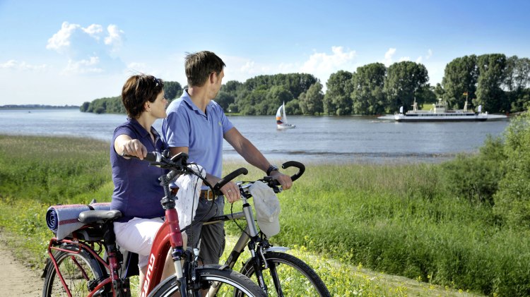 Zwei Radfahrer machen bei schönem Wetter eine Pause und schauen auf den Fluss Luhe., © Elberadweg Nord/ J.Harbeck