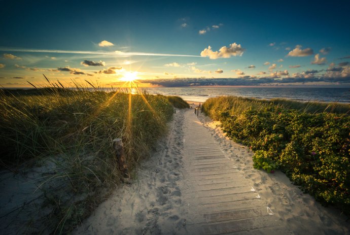 Blick von einer Düne in die untergehende Sonne am Strand von Langeoog, © Tourismus-Service Langeoog/ Andreas Falk