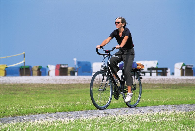 Fahrradfahrerin am Strand, © Ostfriesland Touristik - Landkreis Aurich GmbH