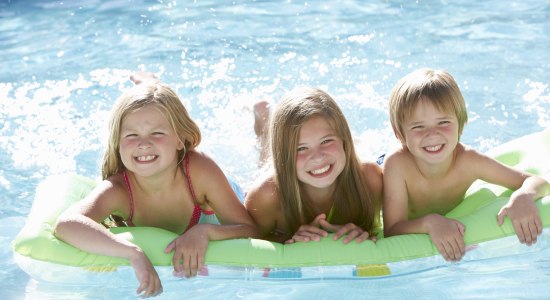 Drei Kinder liegen auf einer Lutfmatratze im Schwimmbad, © Fotolia