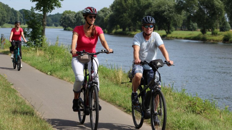 Paar fährt Fahrrad auf Radweg neben der Weser, © Mittelweser Touristik GmbH