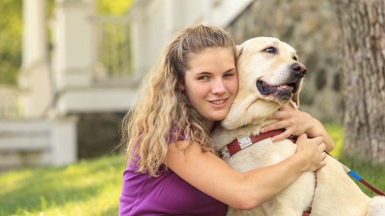 Ein Mädchen umarmt einen Assistenzhund, © fotolia / Mark J. Hunt