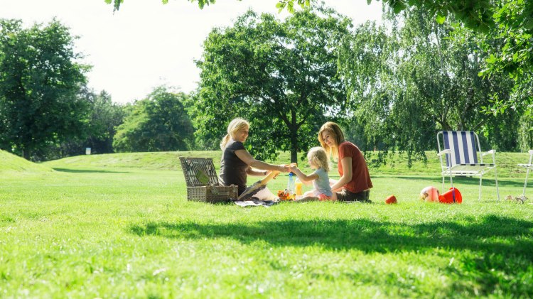 Zwei Frauen und ein Kleinkind machen ein Picknick im Allerpark, © Wolfsburg AG / Jenko Sternberg