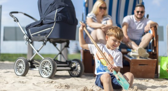 Eltern sitzen im Strandkorb und kleiner Junge gräbt im Sand, © TourismusMarketing Niedersachsen GmbH