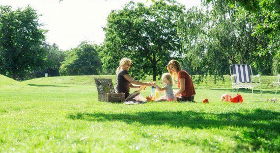 Zwei Frauen und ein Kleinkind machen ein Picknick im Allerpark, © Wolfsburg AG / Jenko Sternberg