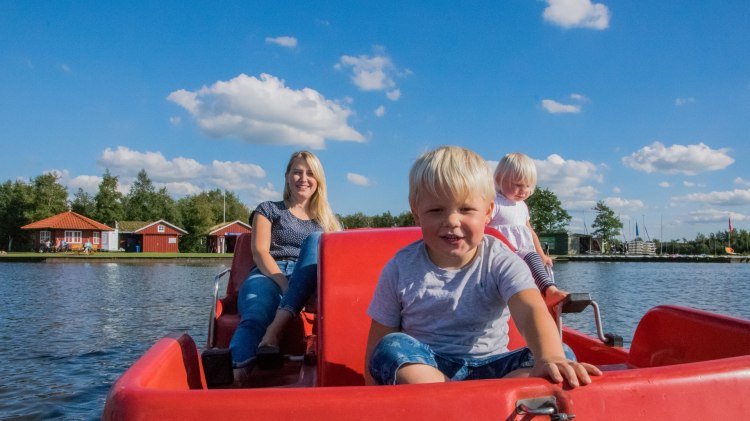 Eine Frau fährt mit ihren zwei Kindern mit einem roten Tretboot., © Südbrookmerland Touristik GmbH