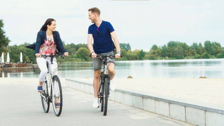 Zwei Radfahrer fahren auf der Promenade am Allersee Rad., © Wolfsburg AG / Jenko Sternberg