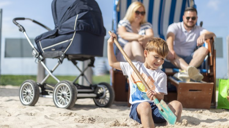 Eltern sitzen im Strandkorb und kleiner Junge gräbt im Sand, © TourismusMarketing Niedersachsen GmbH