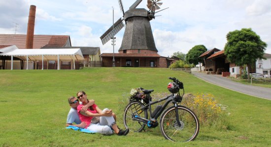 Radfahrer legen Pause neben einer Mühle ein, © Mittelweser Touristik GmbH