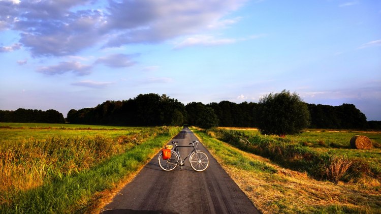 Fahrrad auf Weg zwischen Feldern beim Sonnenuntergang, © Robert Wenzel