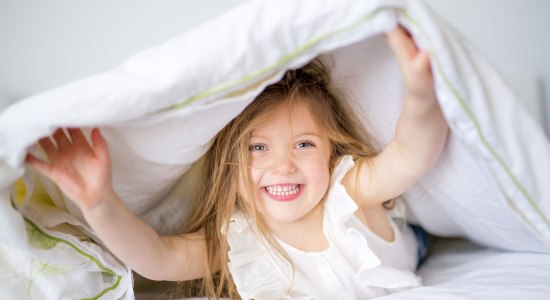 Kind versteckt sich auf dem Bett, © Fotolia