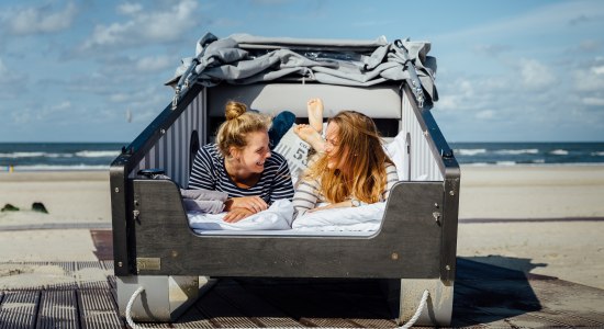 Schlafstrandkorb Norderney in dem zwei Mädchen liegen und sich anlachen, © Staatsbad Norderney GmbH, Janis Meyer